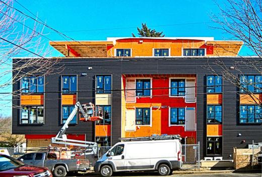 The orange weather-barrier paper on “The Flying Ace” apartment house at S.E. 50th and Woodstock Boulevard will be covered in black metal siding, with a wood siding accent material. At the time of this photo, the orange paper was in the process of being covered by the permanent siding.