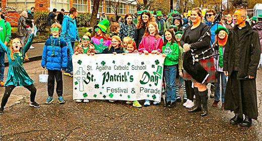 Clearly-enthusiastic students and families of St. Agatha Catholic School lined up on the campus, holding aloft the banner heralding their annual St. Patricks Day Parade  joined (on the far right) by the St. Agathas pastor, Father Luan Tran.