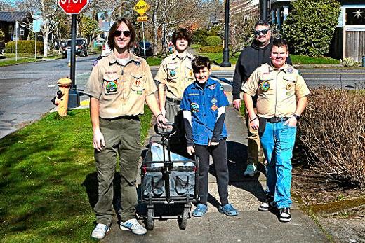 Pulling wagonloads of contributed food, March 1st on S.E. Bybee Boulevard, from left, were BSA Troop 64 Scouts Colby and Ryan Vanderbout, Nicholas Ferguson  parent Tim Ferguson  and Carter Ferguson. It was the annual Scouting for Food drive in Inner Southeast.