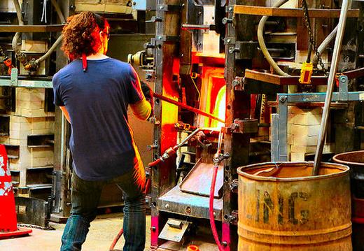A Bullseye Glass worker pulls another load of molten glass, soon to become art glass, from a furnace at the Brooklyn neighborhood facility, known around the world for its high-quality art glass