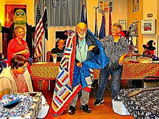 Dolores Tallmadge (at right) helps place a Quilt of Valor around Navy Veteran Myron Boyer, a Woodstock resident. This quilt of comfort was sewn by many hands.